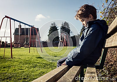 Lonely child sitting on play park playground bench Stock Photo