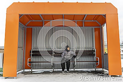 lonely child waiting for a bus at an empty bus stop in winter Stock Photo