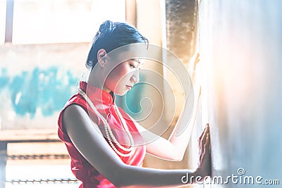 Lonely Chinese woman looking out the light on the windows with sadness Stock Photo