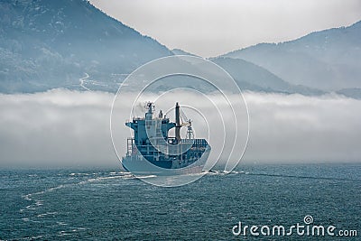 Lonely container carrier ship sailing bound in thick sea fog Stock Photo