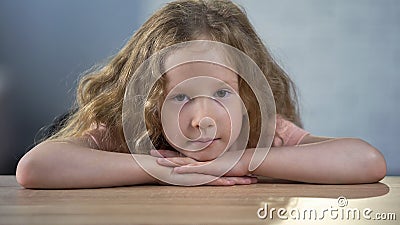 Lonely depressed blond girl sitting alone at table, looking to camera, adoption Stock Photo