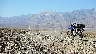 Lonely dual sport motorcycle on empty dirt road in Death Valley desert in United States Stock Photo