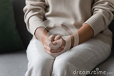 Lonely elderly woman put hands on laps sitting on couch Stock Photo