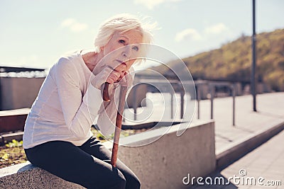 Lonely elderly woman resting after a long tiring walk Stock Photo