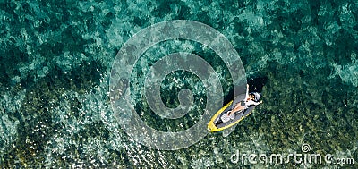 A lonely female in a straw hat smiling, relaxing lying floating in a kayak on the turquoise Adriatic Sea waves. Aerial coastal top Stock Photo