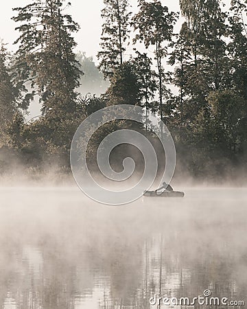 A lonely fisherman in a boat on the river on a foggy morning. Editorial Stock Photo