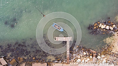 Lonely fishing boat and wooden pier in turquoise ocean, sea. Aerial photo, top view Stock Photo