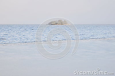 Lonely island in fog with partially frozen waters of lake at foreground Stock Photo