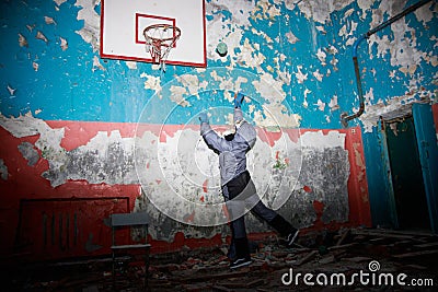 Lonely kid girl in abandoned old children school, oldish walls with cracked paints yellow blue green walls, forsaken strange left Stock Photo
