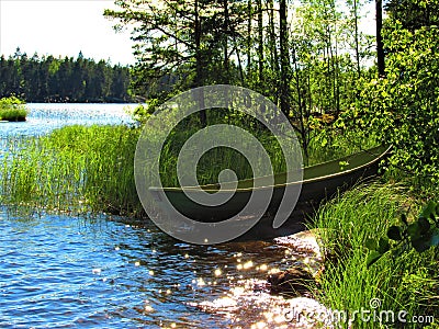 View of a lonely lake beach with green boat Stock Photo