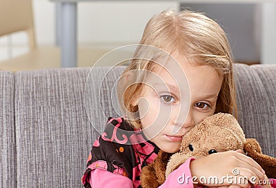 Lonely little girl sitting sadly on sofa Stock Photo