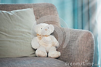Lonely, loss and adoption with a teddy bear abandoned on a sofa in an empty living room of a home. Lost, alone and grief Stock Photo