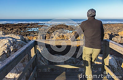 Lonely man from the back on the beach of Atlantic ocean, Portugal. Quiet morning on Atlantic ocean coast. Seascape with cliffs. Stock Photo