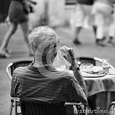 Lonely man is having breakfast. Senior man in street cafe Editorial Stock Photo