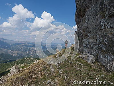 Lonely man hiker walking around limestone tower Perda Liana, impressive rock formation on green forest hill, sardinian Editorial Stock Photo