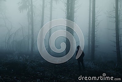Lonely man, a man stands between tree trunks on a blurry background of a foggy forest, mysterious mystical concept Stock Photo