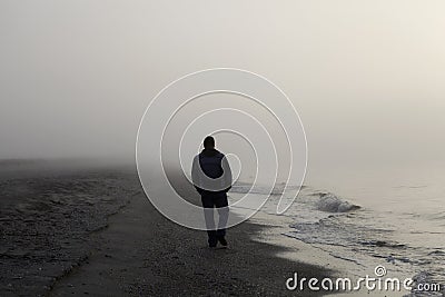 Lonely man walking on a beach Stock Photo