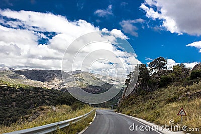 Lonely and moody road with clouds and an interesting light. Mountain road with dramatic colourful sky. Journey, outdoor, travel Stock Photo