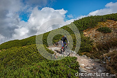 Lonely mountain cyclist on rocky trail high in the mountains. Kasprowy Wierch, Tatra Mountains, Poland. Editorial Stock Photo