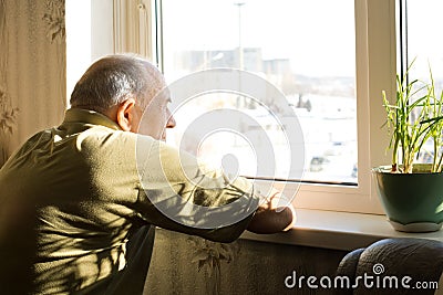 Lonely old man staring out of a window Stock Photo