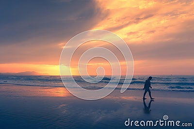 Lonely person walking on beach at sunset Stock Photo