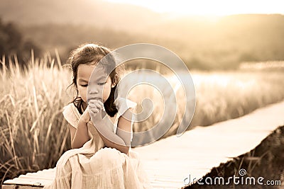 Lonely and sad little girl sitting on bamboo walkway Stock Photo