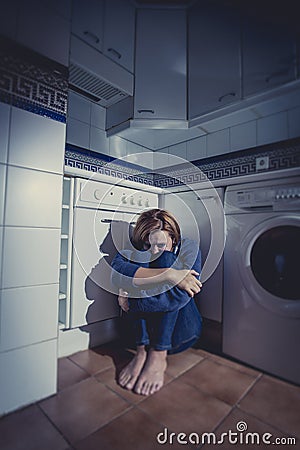 Lonely and sick woman sitting on kitchen floor in stress depression and sadness Stock Photo