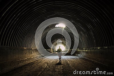 Lonely silhouette in dark tunnel goes to the light . Man walking to the light . Stock Photo