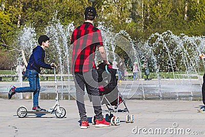 Lonely single father hipster in checkered red and black shirt with a stroller walking in the city park Editorial Stock Photo