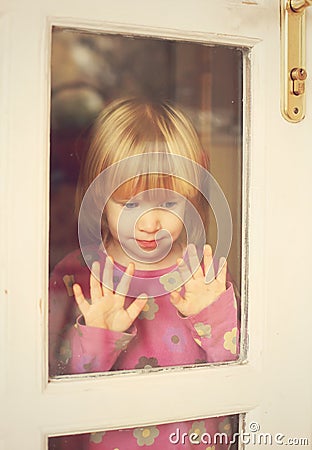 Sorrowful child stand at door window Stock Photo