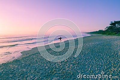 Lonely surfer with surfboard walking on ocean beach. Stock Photo