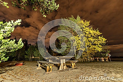 Lonely Swedish beach with bonfire place and wooden outdoor table benches at autumn night, Vasterbotten province Stock Photo
