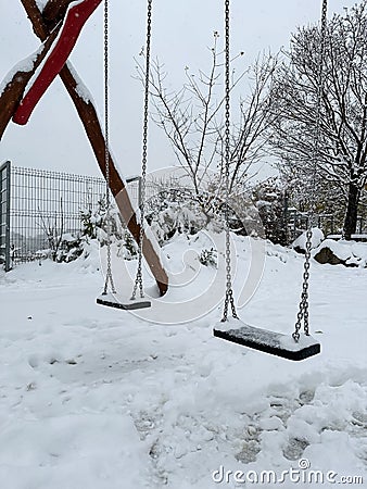 Lonely swings at empty children's playground covered with snow. Winter solitude. Prague. Stock Photo