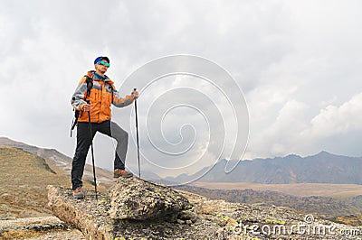 A lonely tourist enjoys the views high in the mountains where there is no grass of the village and snow Stock Photo