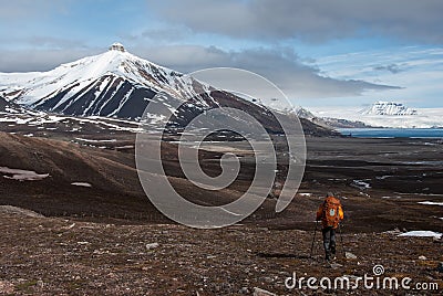 Lonely tourist hiking towards snow capped mountain in the Russian ghost town Pyramiden in Svalbard archipelago Stock Photo