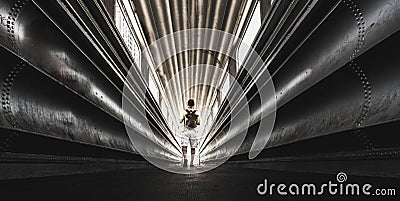 Lonely traveler man with backpack wolking in a steel urban tunnel - city tourism in rare scenic places concept - exploring outdoor Stock Photo