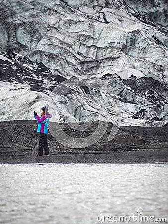 Lonely turist girl near a glacier taking pictures Stock Photo