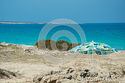 Lonely umbrella on rocky beach Stock Photo