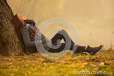 Lonely woman having rest under the tree near the water in a foggy autumn day Stock Photo