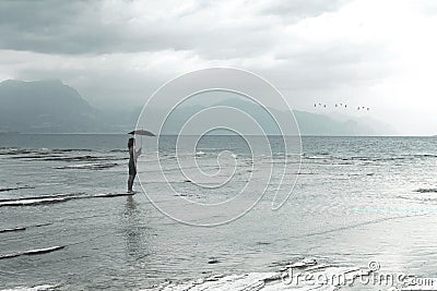 Lonely woman looks at infinity and uncontaminated nature on a stormy day Stock Photo