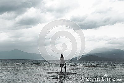 Lonely woman looks at infinity and uncontaminated nature on a stormy day Stock Photo