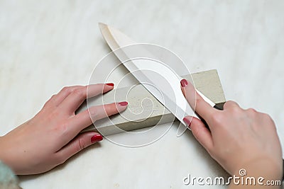 Lonely woman sharpening a knife on a grindstone in the kitchen Stock Photo