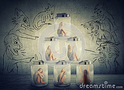 Lonely woman sitting in a pile of glass jars surrounded by angry negative evil men Stock Photo