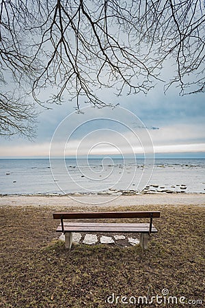 Lonely wooden bench on the autumn sea with cloudy sky Stock Photo