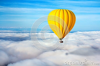 A lonely yellow hot air balloon floats above the clouds. Concept leader, success, loneliness, victory Stock Photo