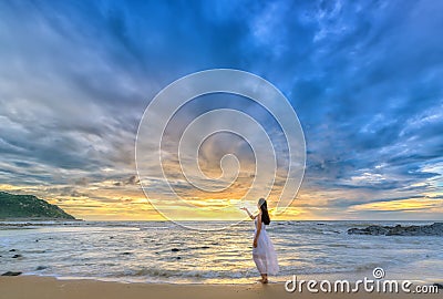 Lonely young woman stands alone on the beach looking towards the end of the vast horizon Editorial Stock Photo