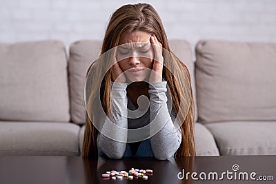 Lonely young woman suffering from severe depression, wanting to commit suicide by overdosing on pills at home Stock Photo