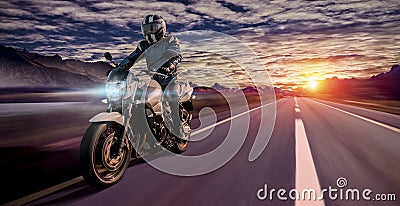 Lonesome biker on the highway at dawn of a cloudy day Stock Photo