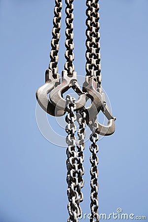 Long chains with hooks hanging vertically against blue sky Stock Photo