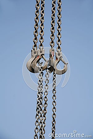 Long chains with hooks hanging vertically against blue sky Stock Photo